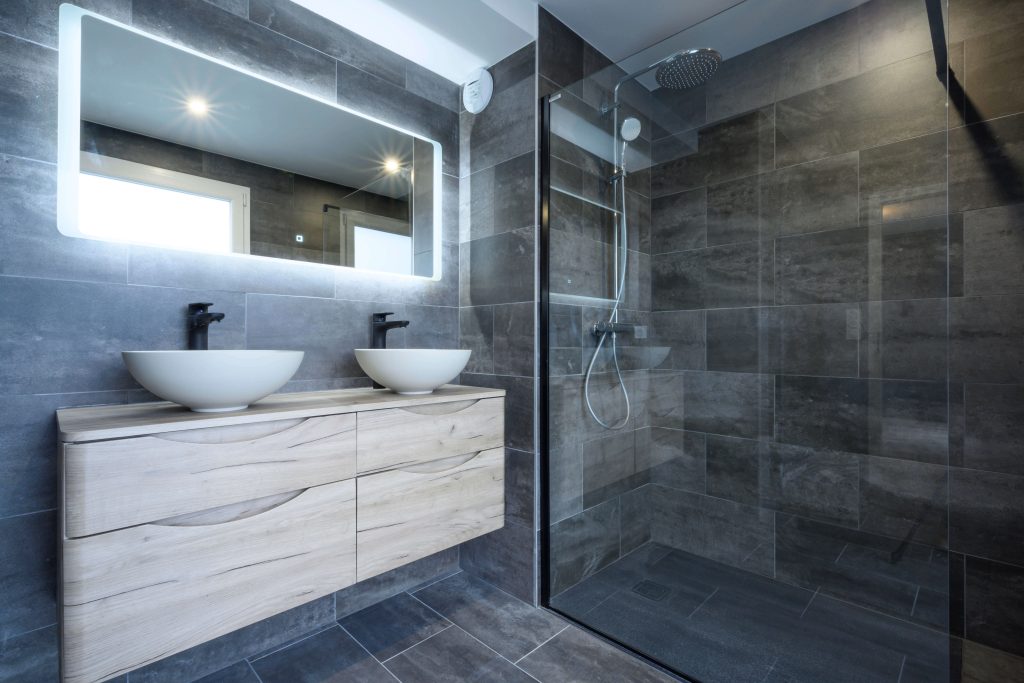 Grande salle de bain lumineuse avec douche à l'italienne, double vasque et miroir lumineux